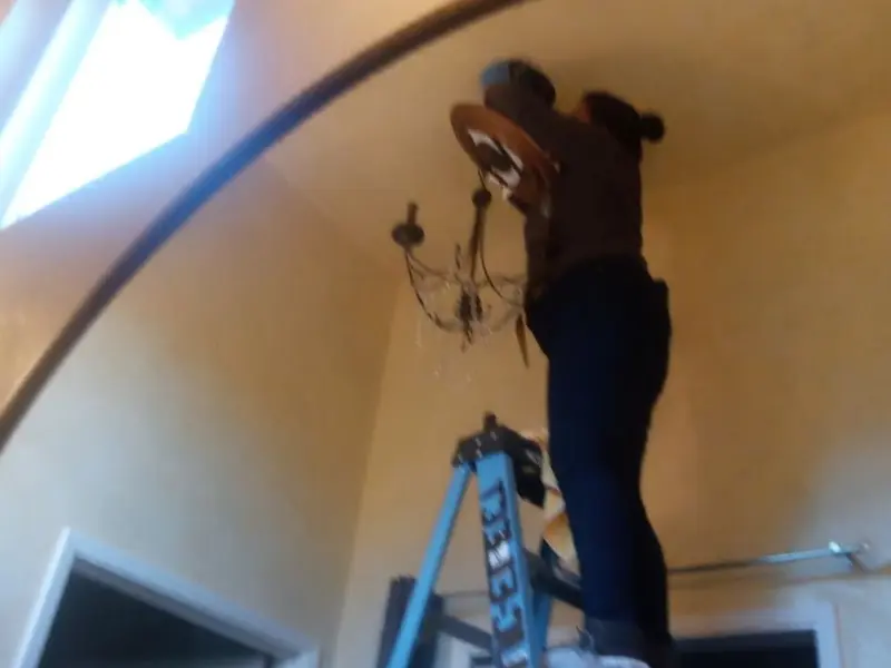 Electrician installing a chandelier in a Lindsay residence